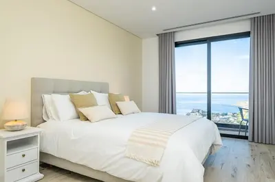 a white bedroom with a large bed and a large window at Casa Isabel in Ribeira Brava