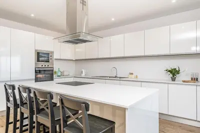 a kitchen with white cabinets and a island with chairs at Casa Isabel in Ribeira Brava
