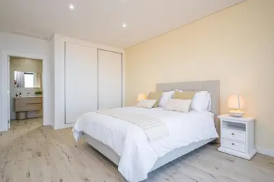 a white bedroom with a large bed and a bathroom at Casa Isabel in Ribeira Brava