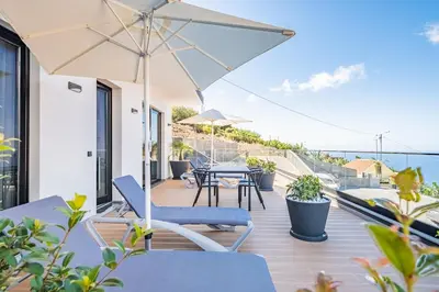 a balcony with a table and chairs and an umbrella at Casa Isabel in Ribeira Brava