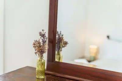 a vase with flowers in it next to a mirror at GuestReady - Hillside Escape I in Câmara de Lobos