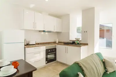 a kitchen with white cabinets and a table at GuestReady - Hillside Escape I in Câmara de Lobos