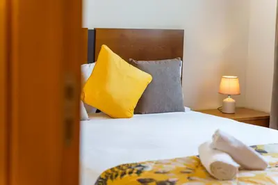 a bedroom with a bed with yellow and gray pillows at GuestReady - Madeiran mountain view with pool in Santa Cruz