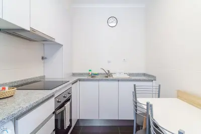 a kitchen with white cabinets and a sink at GuestReady - Madeiran mountain view with pool in Santa Cruz