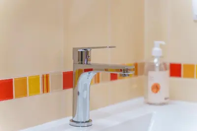 a bathroom sink with a faucet and a bottle of soap at GuestReady - Madeiran mountain view with pool in Santa Cruz