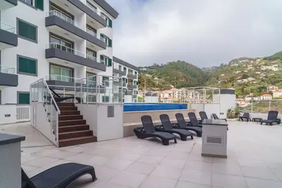 a balcony of a building with chairs and a swimming pool at GuestReady - Madeiran mountain view with pool in Santa Cruz