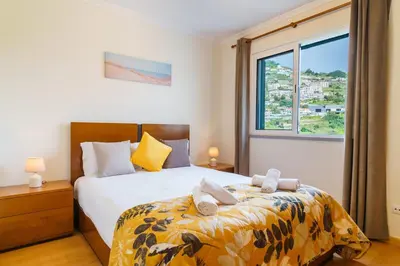 a bedroom with a bed and a large window at GuestReady - Madeiran mountain view with pool in Santa Cruz