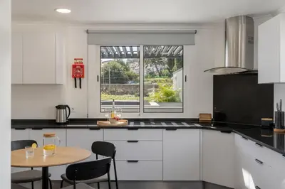 a white kitchen with a table and a window at Casa Tabaibo by An Island Apart in Funchal