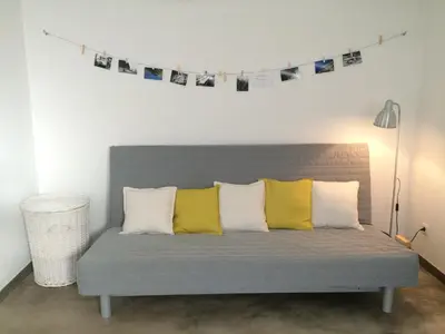 a gray couch with four pillows and a string of photos at Aqua Sea House in Madalena do Mar