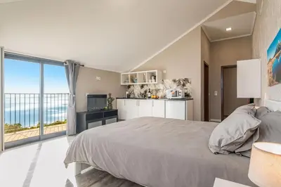 a balcony with a table and chairs and the ocean at Madeira Sunrise Villa in Gaula