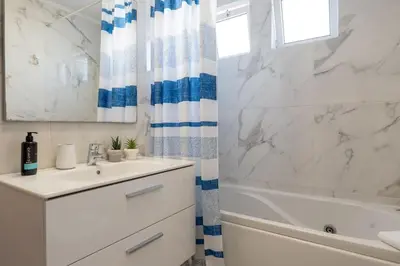 a white bathroom with a sink and a tub and a mirror at Conde Casa Branca by LovelyStay in Funchal