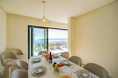 a table with wine glasses and a stove with the ocean at Villa Infinityviews Madeira in Câmara de Lobos