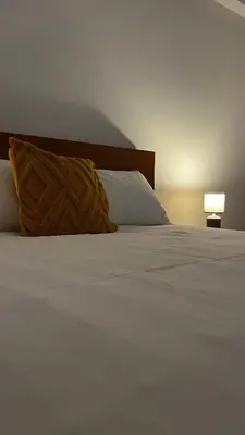 a white bed with a pillow and a lamp at Brisa do Norte apartment in São Vicente