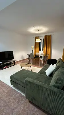 a living room with a green couch and a table at Brisa do Norte apartment in São Vicente
