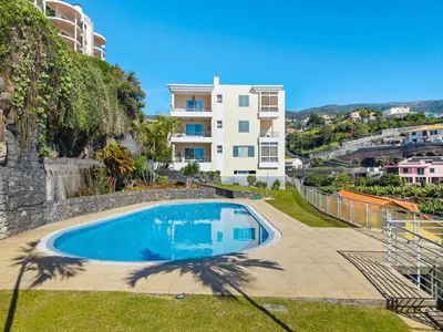 a swimming pool in front of a building at Peace Haven II in Calheta