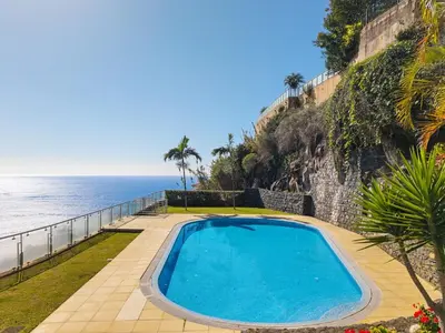 a swimming pool next to the ocean at Peace Haven II in Calheta