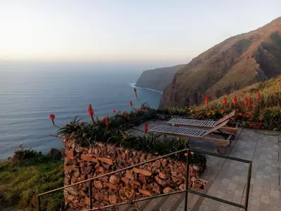 a bench on the side of a cliff overlooking the ocean at Holiday Home Erdhaus by Interhome in Fajã da Ovelha
