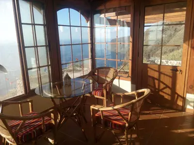 a glass table and chairs in a room with windows at Holiday Home Erdhaus by Interhome in Fajã da Ovelha