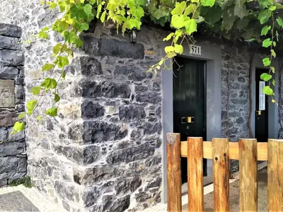 a stone house with a black door and a wooden fence at Holiday Home Casa Lugar da Ribeira mit Dachterrasse by Interhome in Campanário