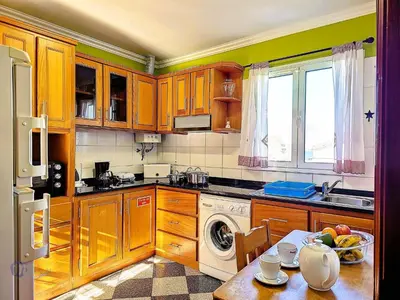 a kitchen with wooden cabinets and a table with a dishwasher at Apartment Domus Dino by Interhome in Porto da Cruz
