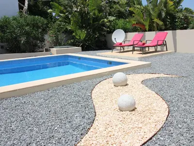 a swimming pool with two pink chairs next to it at Holiday Home Vila Marques da Luz by Interhome in Montinhos da Luz