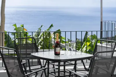 a bottle of wine sitting on a table with two glasses at OurMadeira - Casa da Vinha in Câmara de Lobos