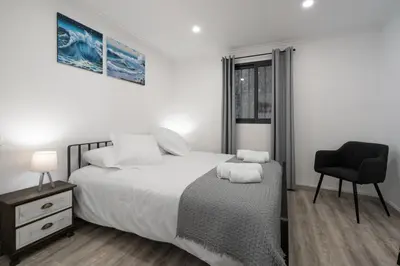 a white bedroom with a bed and a chair at OurMadeira - Casa da Vinha in Câmara de Lobos