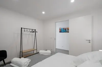 a white bedroom with a bed and a chair at OurMadeira - Casa da Vinha in Câmara de Lobos