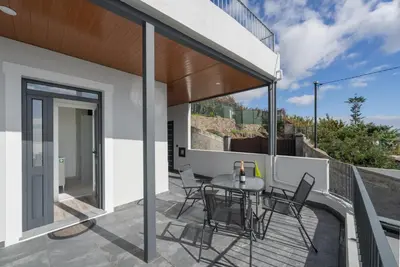 a patio with a table and chairs on a balcony at OurMadeira - Casa da Vinha in Câmara de Lobos