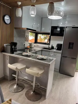 a kitchen with a counter and two bar stools at O Refúgio in Calheta