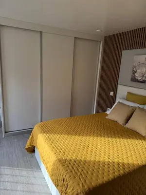 a bedroom with a yellow bed with sliding glass doors at O Refúgio in Calheta
