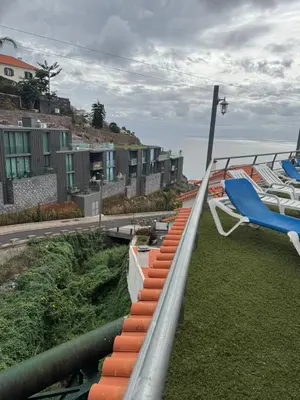 a balcony with a blue lounge chair and the ocean at O Refúgio in Calheta