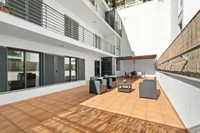 an internal courtyard of a building with chairs and a table at Lido Retreat Apartment in Funchal