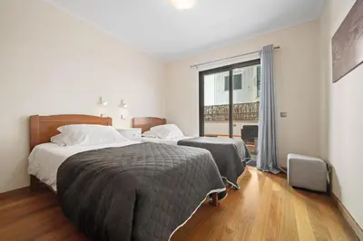 a bedroom with two beds and a large window at Lido Retreat Apartment in Funchal