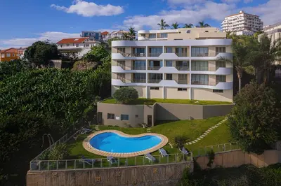 a large white building with a swimming pool in front of it at New Calheta Plaza Apartment by Your Madeira Rentals in Estreito da Calheta