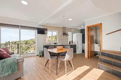a kitchen and living room with a table and chairs at Casa da Feira in Calheta
