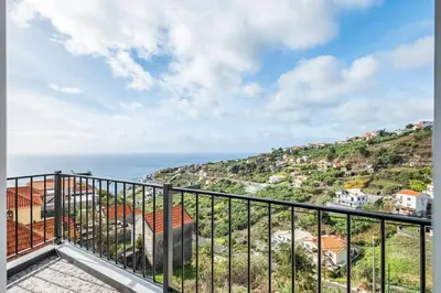 a kitchen and living room with a table and chairs at Casa da Feira in Calheta
