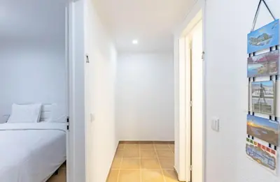 a white bedroom with a bed and a hallway at MG Hollidays - Av Infante Funchal in Funchal