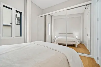 a white bedroom with a bed and a mirror at Solar dos Reis in Funchal
