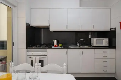 a kitchen with white cabinets and a table with chairs at Pico Views by An Island Apart in Câmara de Lobos