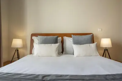 a large bed with white pillows and two lamps at Pico Views by An Island Apart in Câmara de Lobos