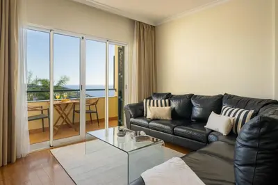 a living room with a black leather couch and a glass table at Pico Views by An Island Apart in Câmara de Lobos