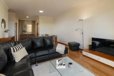 a living room with a black leather couch and a television at Pico Views by An Island Apart in Câmara de Lobos