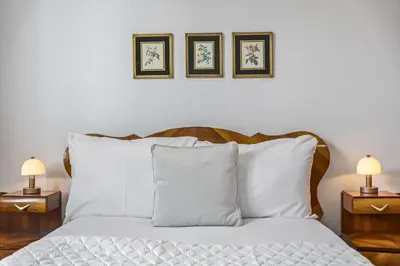 a bedroom with a bed with white pillows and two lamps at Reis by KAAMAH in Ribeira Brava