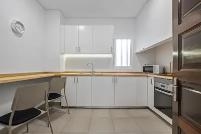 a kitchen with white cabinets and a table and chairs at Reis by KAAMAH in Ribeira Brava