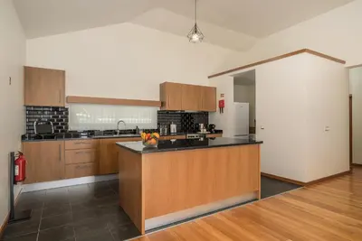 a large kitchen with wooden cabinets and a counter top at Rosas House, private house with jacuzzi and BBQ in Estreito da Calheta