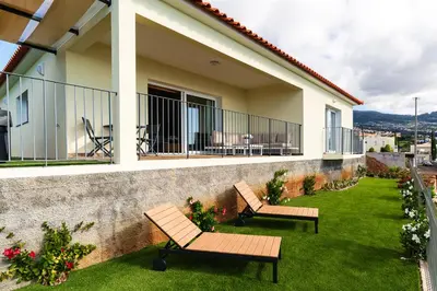 two benches sitting on a lawn in front of a house at Rosas House, private house with jacuzzi and BBQ in Estreito da Calheta