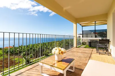 a balcony with a table and a view of the ocean at Rosas House, private house with jacuzzi and BBQ in Estreito da Calheta