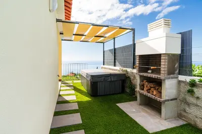 a backyard with a hot tub and a grill at Rosas House, private house with jacuzzi and BBQ in Estreito da Calheta