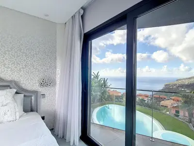 a bedroom with a large window with a view of a swimming pool at Holiday Home VILLA BONSAI by Interhome in Arco da Calheta